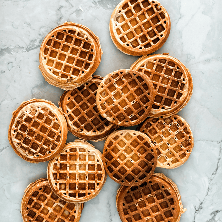 Golden brown waffles with crispy grid pattern arranged on white marble countertop from overhead view
