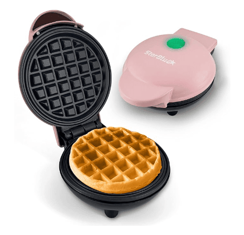 Pink mini waffle maker with non-stick plates showing open lid with golden round waffle inside